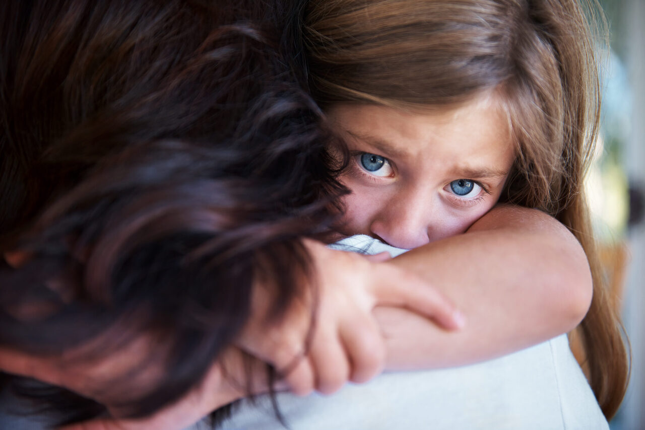 Closeup shot of a upset little girl hugging her mom around the neck